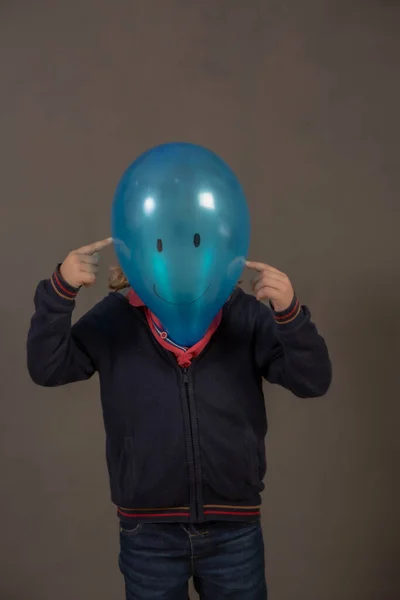 Painted blue balloon head with a happy face on a child\'s body