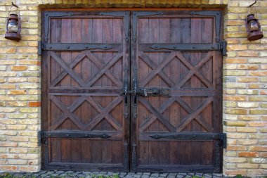 Wooden double-leaf gates on a concrete structure. Naturally patterned boards. Metal hinges and handles.