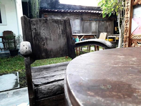 an old wooden chair with a faded black color side by side with a brown wooden table located at the back of the house