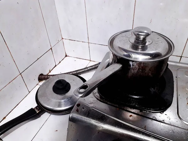 these small stainless and teflon pots that are visible on the kitchen table and on the stove are used by grandma to cook the family's favorite meals