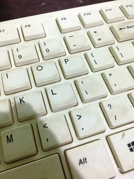 a white keyboard that looks dirty due to hand stains and is rarely cleaned by the owner