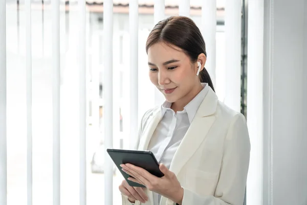Professional marketing leader uses in-depth analytics tablet to advance the organizational structure, Using a laptop for telecommunication work, Works in a modern office