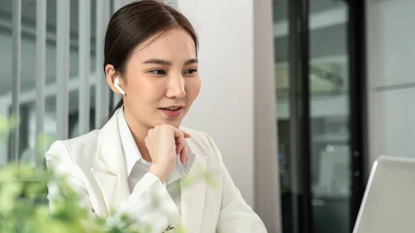 Asian businesswoman uses a laptop to analyze a company\'s financial business graph, Using a laptop for telecommunication work, Happy woman working in front of laptop screen, Modern private office room.