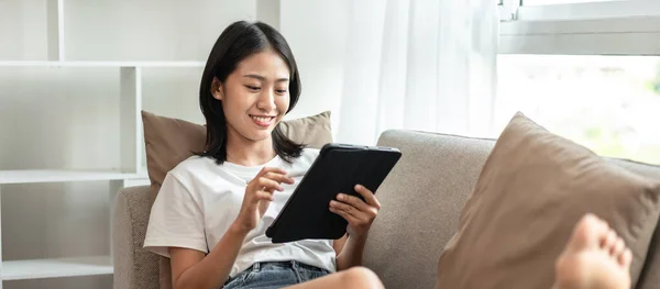 Half Ιαπωνική Γυναίκα Κάθεται Στον Καναπέ Χρησιμοποιώντας Tablet Ενώ Στις — Φωτογραφία Αρχείου