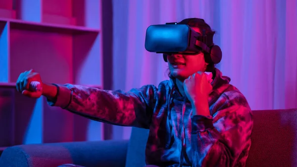 Young man wearing virtual reality (VR) glasses and uses joystick to play games with fun playing games in a room with red and blue lights, 3D game, Future games, Gadgets, Technology, Game concept.