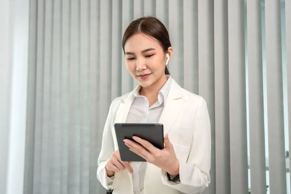 Professional marketing leader uses in-depth analytics tablet to advance the organizational structure, Using a laptop for telecommunication work, Works in a modern office.