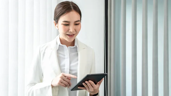 Professional marketing leader uses in-depth analytics tablet to advance the organizational structure, Using a laptop for telecommunication work, Works in a modern office.