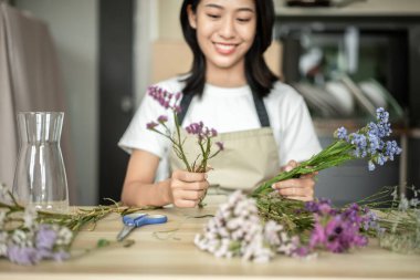 Weekend with her hobbies, Asian woman arranges a bouquet of flowers to decorate her home and beautify, Artificial flower arrangement, living room decoration ideas, Flowers bunch, Arts and crafts.
