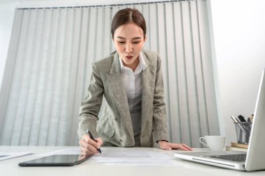Asian business women are analyzing company sales statistical graphs to develop them furthe