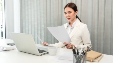 Professional businesswoman analyzing graph data from document in hand, Market research reports and income statistics, Woman working in a private office, Financial and Accounting concept.
