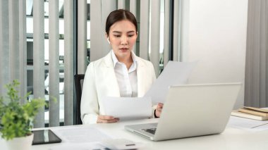 Professional businesswoman analyzing graph data from document in hand, Market research reports and income statistics, Woman working in a private office, Financial and Accounting concept.