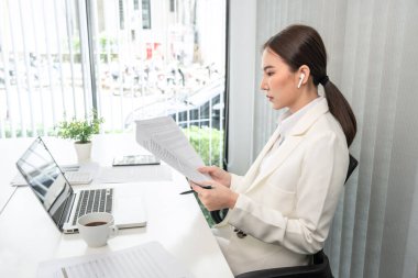 Professional businesswoman analyzing graph data from document in hand, Market research reports and income statistics, Woman working in a private office, Financial and Accounting concept.