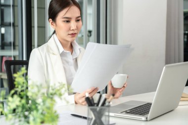 Professional businesswoman analyzing graph data from document in hand, Market research reports and income statistics, Woman working in a private office, Financial and Accounting concept.