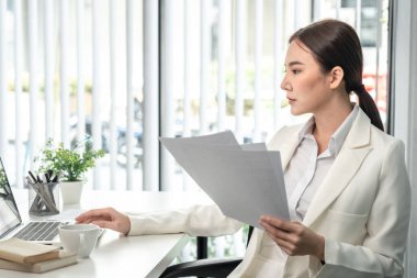 Professional businesswoman analyzing graph data from document in hand, Market research reports and income statistics, Woman working in a private office, Financial and Accounting concept.