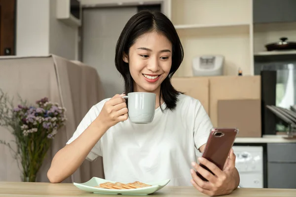 Asian Woman Eats Crackers Breakfast Uses Her Mobile Phone Check — Fotografia de Stock