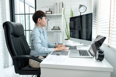 Male programmer is programing to developing program app and website of corporate while working to checking program code and debugging on multiple screen at modern software office.