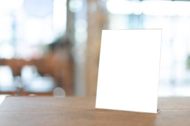 Restoran menüsü çerçevesi. Restorandaki ahşap masa üzerinde beyaz boş ekran. Ya da Bokeh arka planındaki kafe..