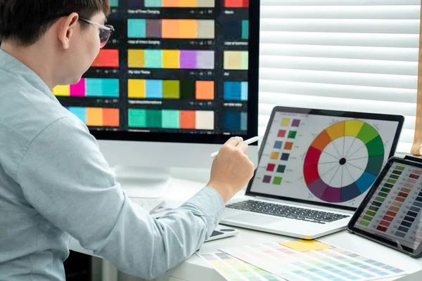 Erkek grafik tasarımcısı birçok ekrandan renk örnekleri seçiyor ve modern ofiste teknolojiyle çalışan grafik tasarımı için tablet dijital üzerinde çizim yapıyor..