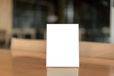 Restorandaki ahşap masada ya da Bokeh arka planındaki kafede beyaz boş ekranlı menü çerçevesi.