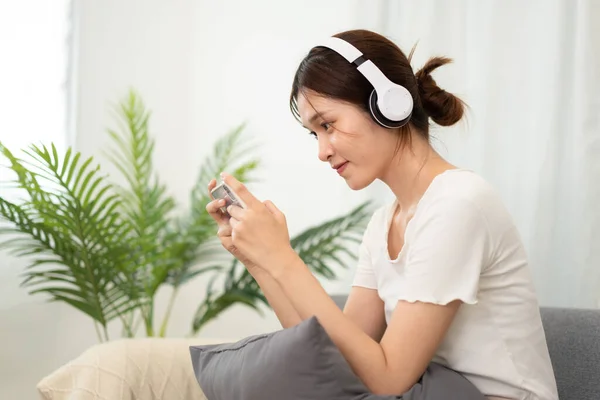 Adolescente Chica Está Usando Auriculares Juegos Teléfono Inteligente Mientras Sienta — Foto de Stock