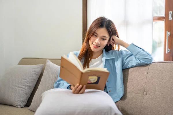 Mujer Joven Está Leyendo Libro Literatura Mientras Está Sentado Sofá — Foto de Stock