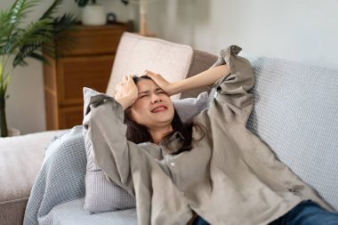 Kadın çalışan kanepeye uzanıyor ve alnına dokunurken yoğun çalıştıktan sonra iş hayatında sorunlar yaşıyor ve hayal kırıklığına uğruyor..