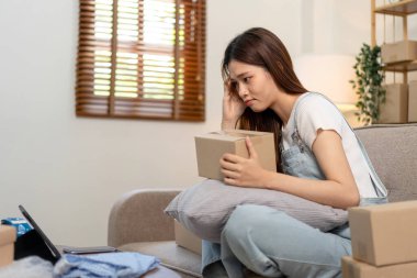 Genç girişimci, online siparişleri ve tabletteki müşteri verilerini kontrol ederken kanepede rahat otururken ve merkez ofisteki oturma odasında çalışırken kendini stresli hissediyor..