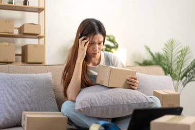 Genç girişimci, online siparişleri ve tabletteki müşteri verilerini kontrol ederken kanepede rahat otururken ve merkez ofisteki oturma odasında çalışırken kendini stresli hissediyor..