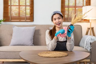 Hizmetçi koruyucu eldiven takıyor ve ev temizliği yaparken vazodaki kiri temizlemek ve temizlemek için mikrofiber bez kullanıyor..