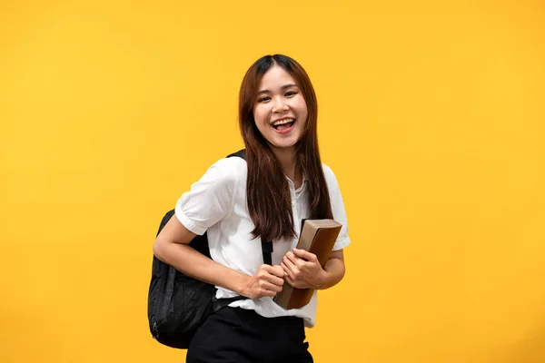 後ろに本とショルダーバッグを持っている女性学生ながら笑顔と黄色の背景に隔離された大学で勉強するための準備 — ストック写真