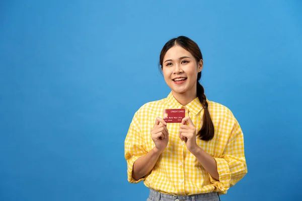 若いアジアの女性は新しいクレジットカードを示すために編組の髪型と笑顔であり ライトブルーの背景に隔離されたオンラインショッピングの準備を夢見ます — ストック写真