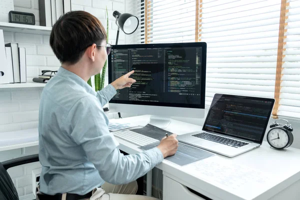Male programmer pointing on screen and programing to developing program app and website of corporate while working to checking program code and debugging on multiple screen at modern software office.
