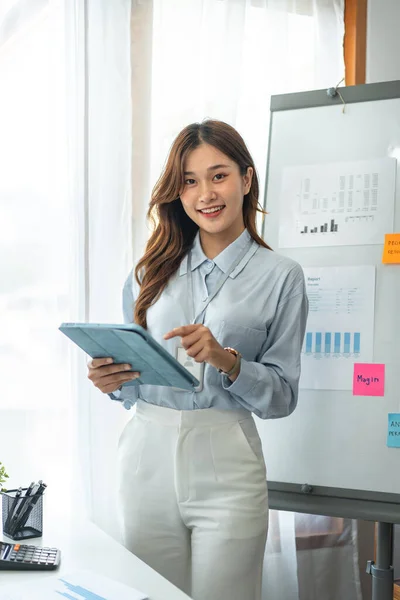 年轻的女商人正在平板电脑上阅读新创企业的数据 并在现代办公室工作时分析企业的战略和规划 — 图库照片