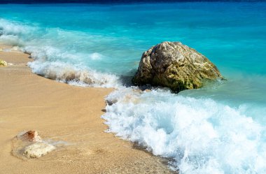 Close up photo of Kaputa beach in Antalya with waves and bubbles.