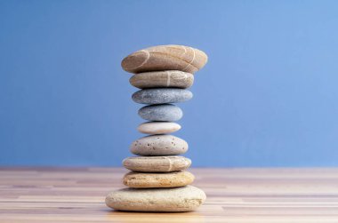 Hand stacking pebbles to make shape of hourglass as a symbol of time management. Concept of meditation, slow down and controlling time.