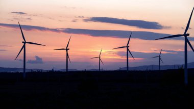 Silhouette photo of wind farm and turbines at sunset. Clean and green energy concept.