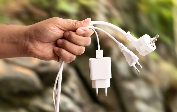 Close up photo of man holding multiple unplugged charging sockets. Concept of energy saving and reduce electricity usage.