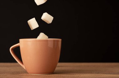 Close up photo of coffee cup and dropping sugar. concept of diabetes and overuse of sugar.
