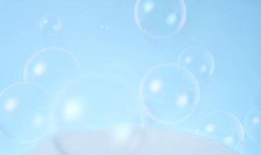 Blurred photo of soap bubbles on blue background.