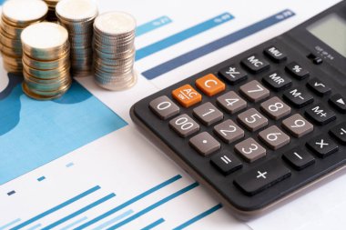 Close up photo of stack of coins and charts and stats with calculator. Concept of accounting , budget and profit.