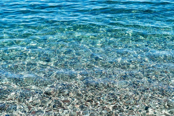 Close up photo of crystal clear water of Olympos beach with pebbles on the bottom in Antalya as a summer, relax, tranquil background.