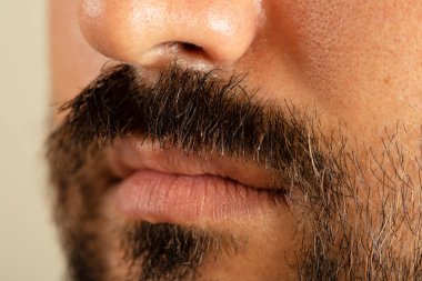 Close up photo of brown skinned man with long facial hair and moustache