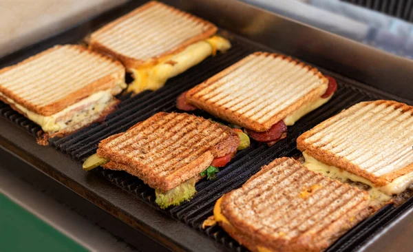 Toasted sandwiches with melting cheese on toaster or grill.