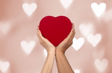 Couples holding heart shaped gift box with bokeh background. Love, gift and present concept.