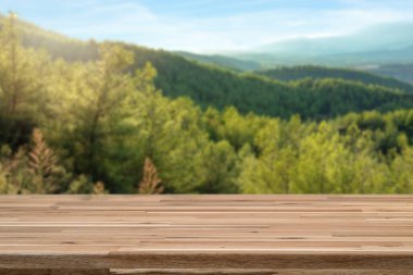 Close up photo of blurred Pine forest and sunny sky on the background and empty tabletop for product montage and display.