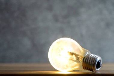 Yeşil bulanık arkaplanda parlayan tek bir ampulün fotoğrafını kapat.