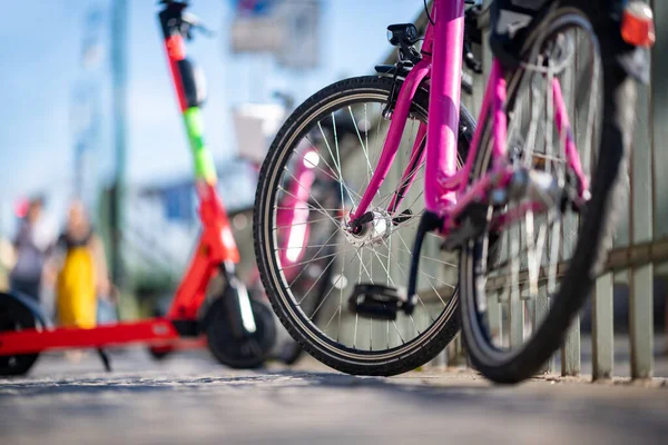 Sokakta arka planda kırmızı elektrikli scooterlı pembe halka açık bisikletin ayrıntıları. Prag 'da modern ekolojik ulaşım kavramı.