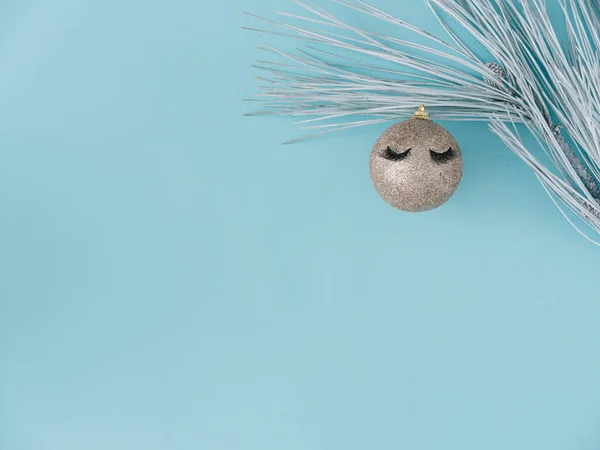 Noel kartı. Pastel mavi arka plan, beyaz köknar ağacı ve sahte kirpikli gümüş parlak Noel mücevherleri. Metnin için kopyalama alanı olan üst görünüm. 