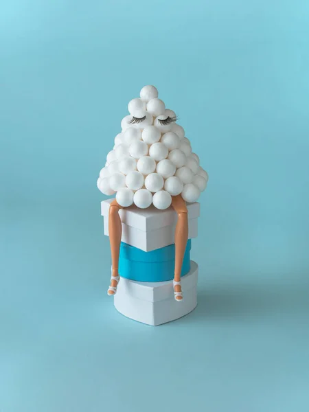 Takma kirpikli yapay Noel ağacından yapılmış bebek bacakları ve pembe yıldız pastel mavi arka planda bir yığın hediyeye oturur. Yaratıcı minimal moda konsepti. Yeni yıl ve mutlu noeller ilham kaynağı