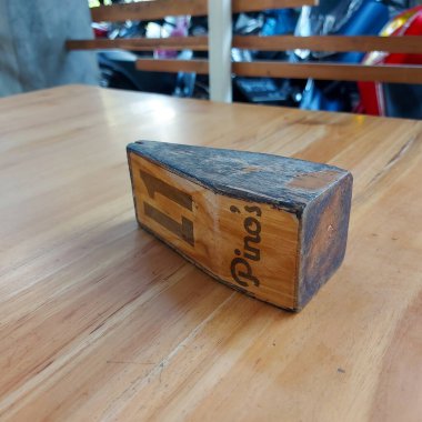 The nameplate is made of thick brown wood.  it is used as a table number sign in a restaurant.  photo taken indoors in the city of gorontalo 14 august 2022